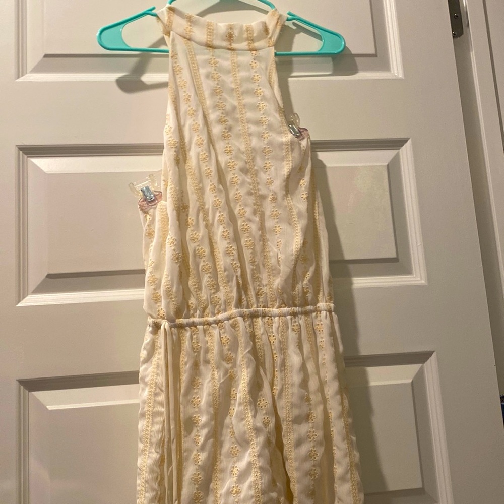 White romper with open back and cream accent flowers